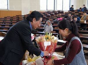弁護士竹内俊雄の画像　駿河大学講堂内で学生から花束を受ける風景