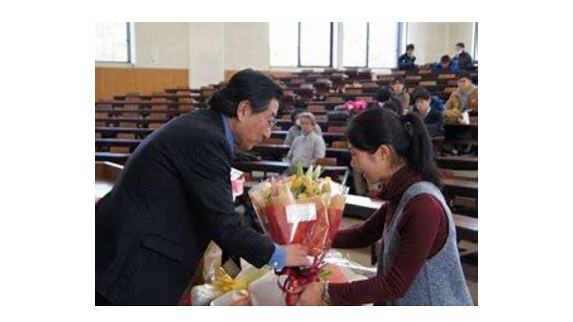 大学構内にて学生から花束を受ける弁護士竹内俊雄